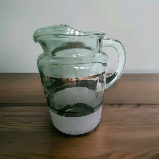 Clear glass pitcher on a wooden surface with a white background