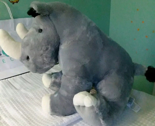 Plush rhino toy on a white surface with a light green wall in the background
