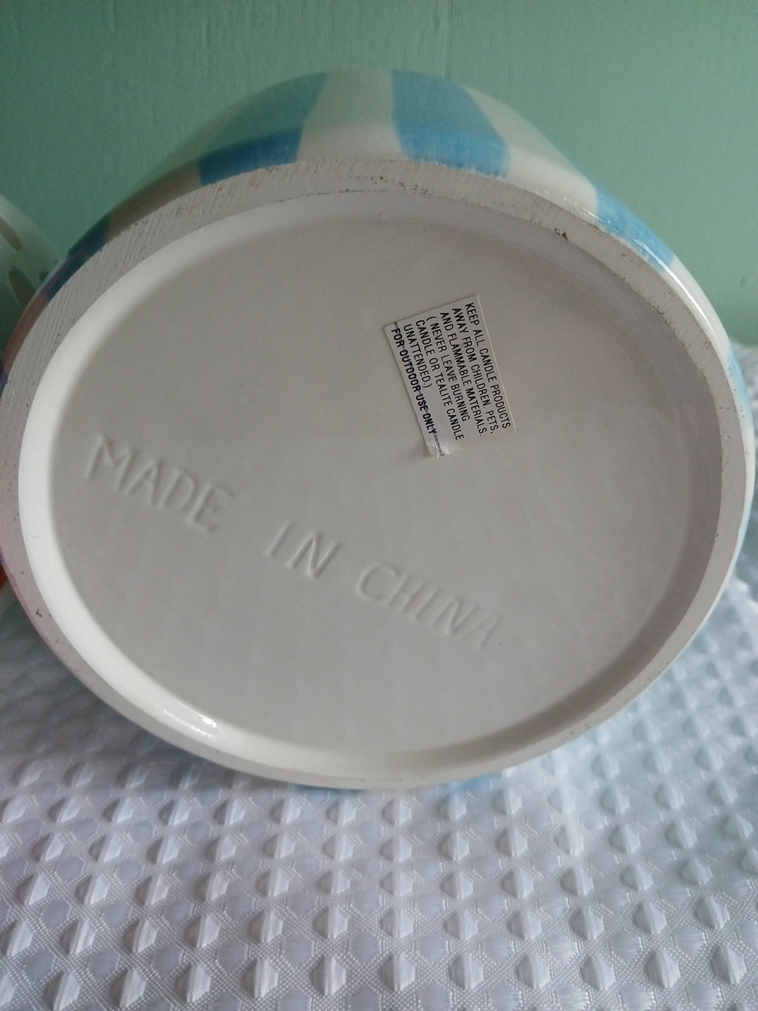 Close-up of a container candle holder lid with 'Made in China' text on a textured surface.