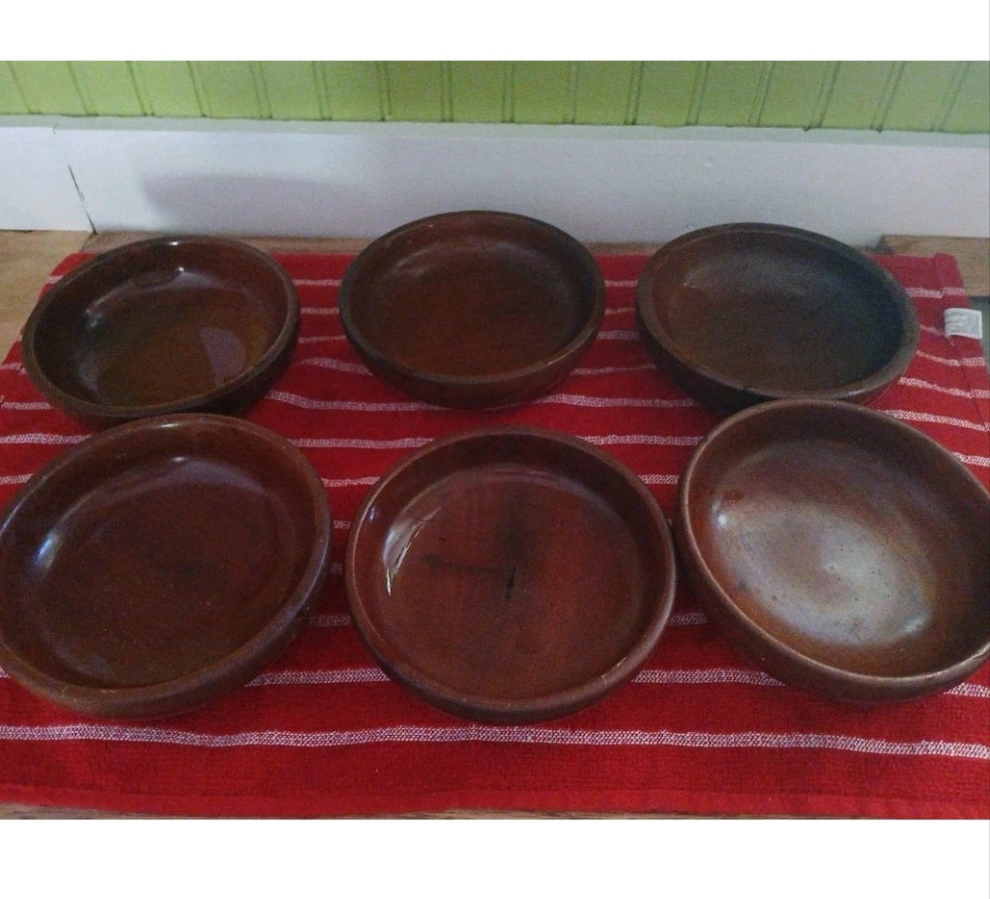 Set of six brown wood bowls on a red and white striped cloth with a green and white background.