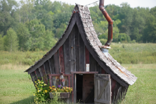Wooden shed in a field with trees in the background