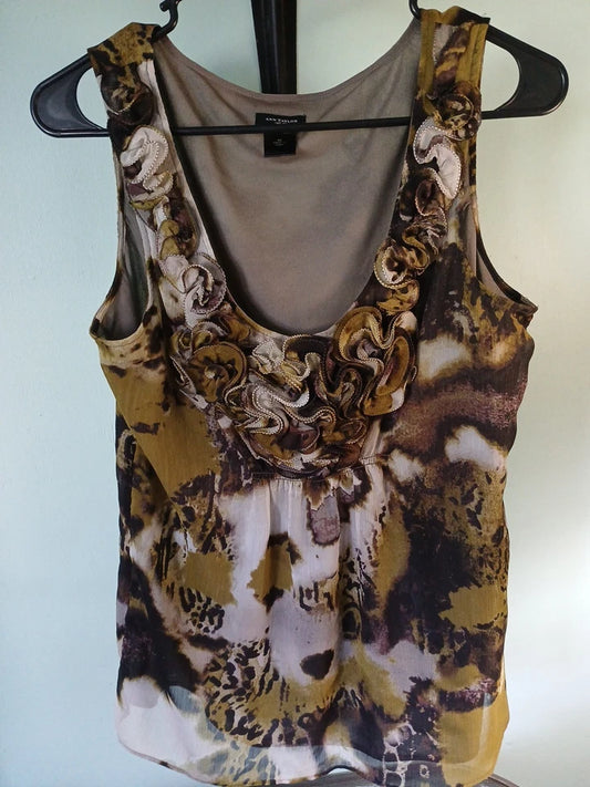 Tank top with floral and animal print design on a hanger against a light blue wall.