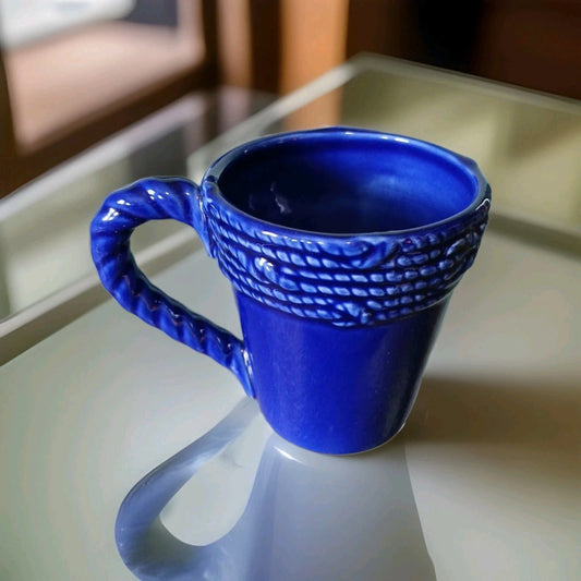 Blue textured mug on a reflective surface with a blurred background