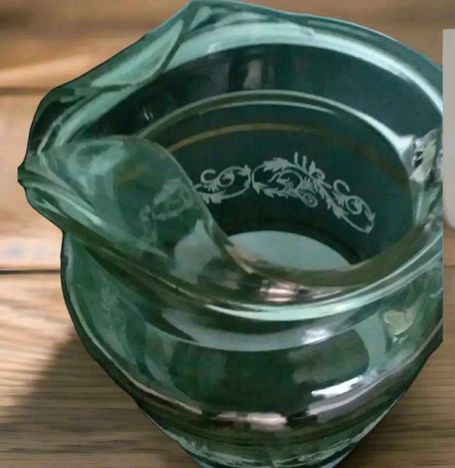 Green glass ashtray with decorative patterns on a wooden surface