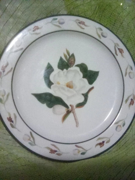 Decorative plate with a white flower design on a green surface