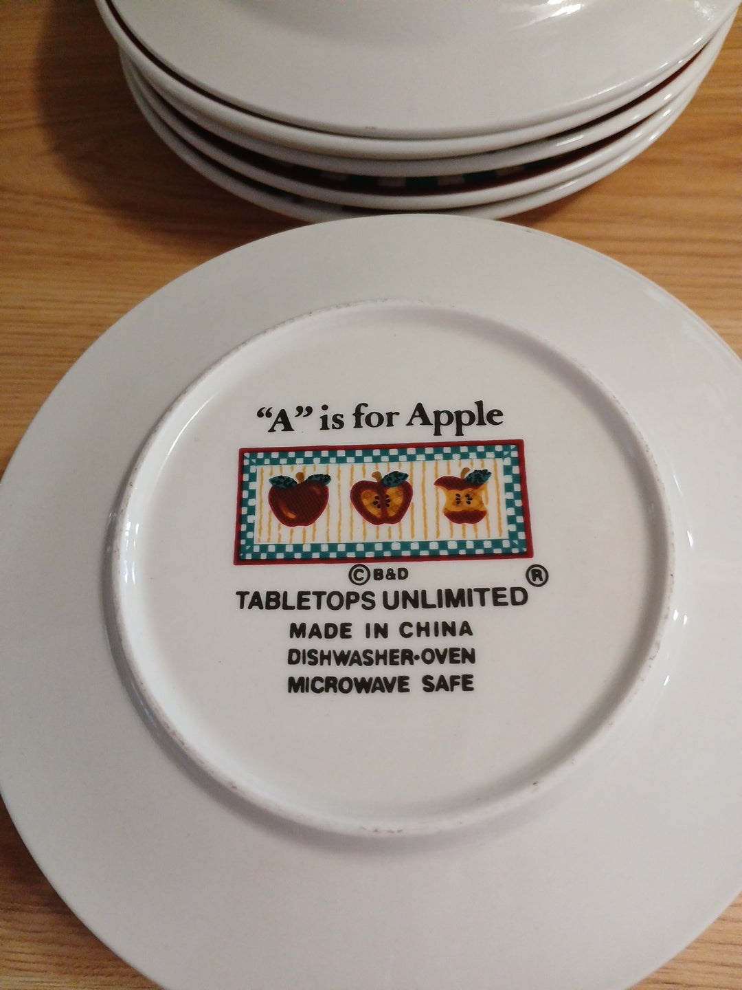 White plate with 'A is for Apple' branding on a wooden surface