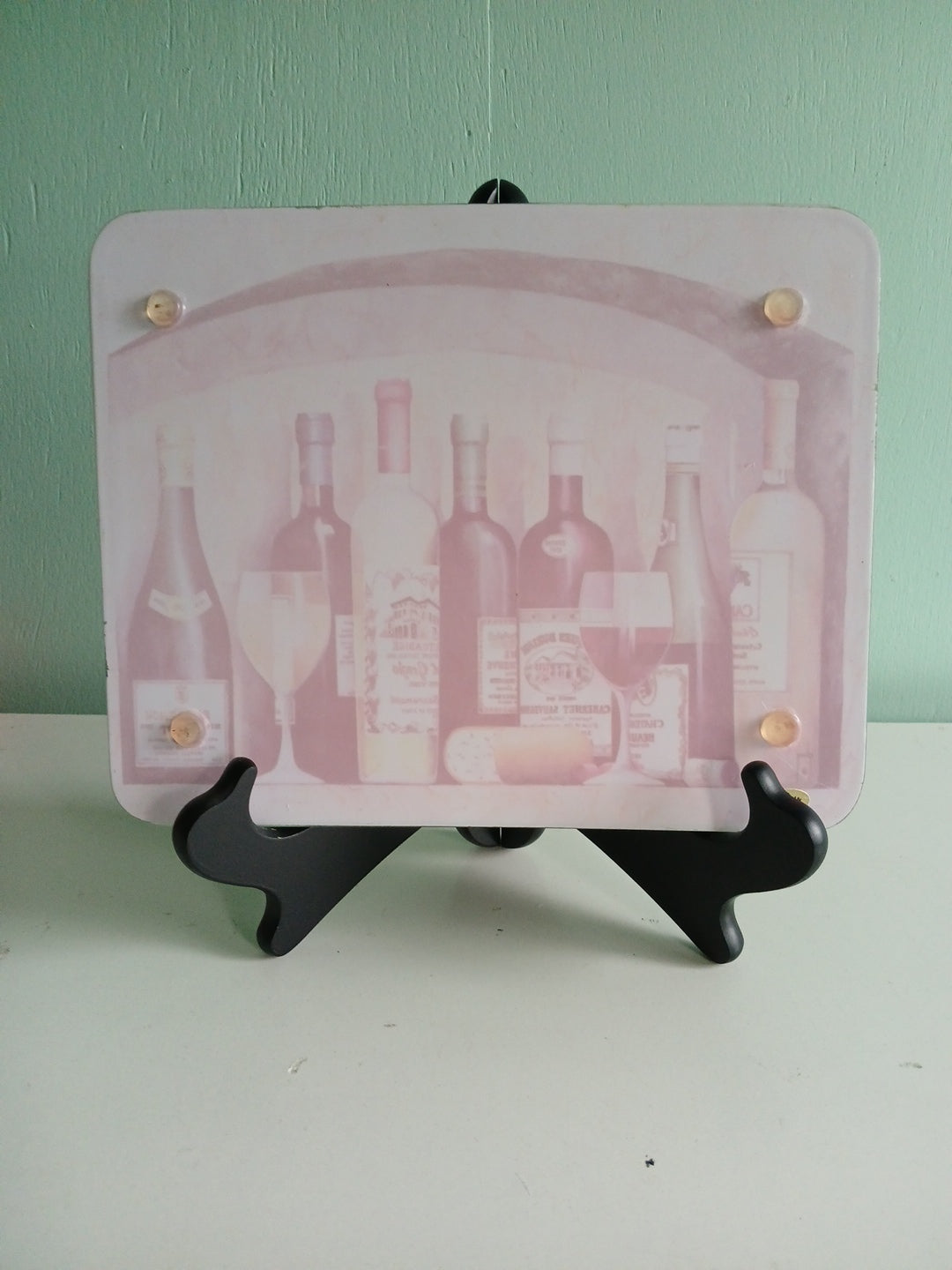 back side of the trivet  featuring bottles on a green and white background
