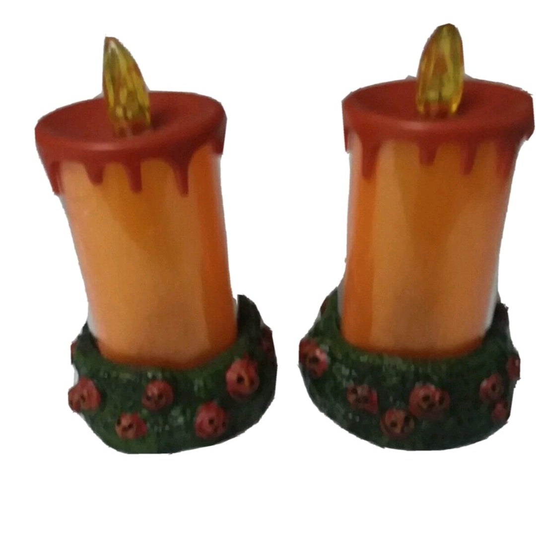 Two candle-shaped figurines with green bases on a white background