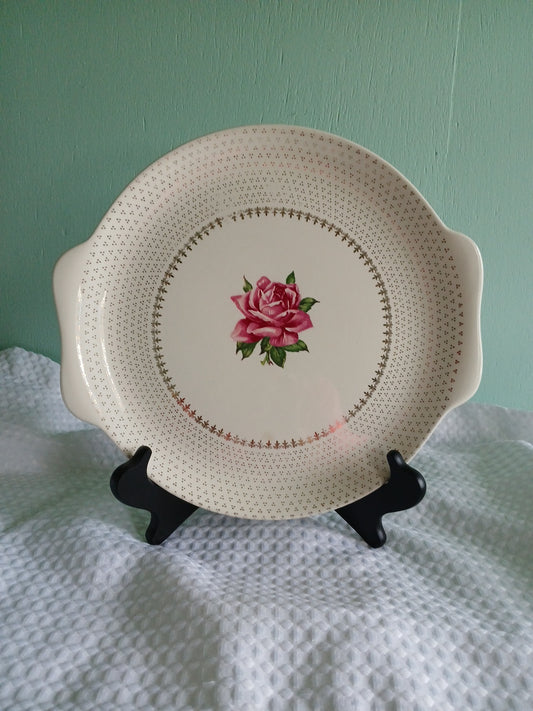 Decorative plate with a rose design on a stand against a light green background