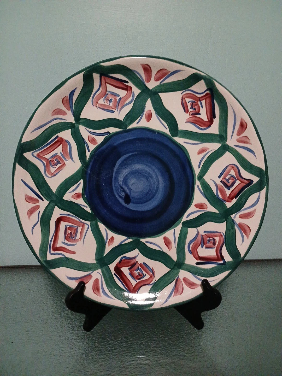 Decorative ceramic plate with geometric pattern on a stand against a plain background