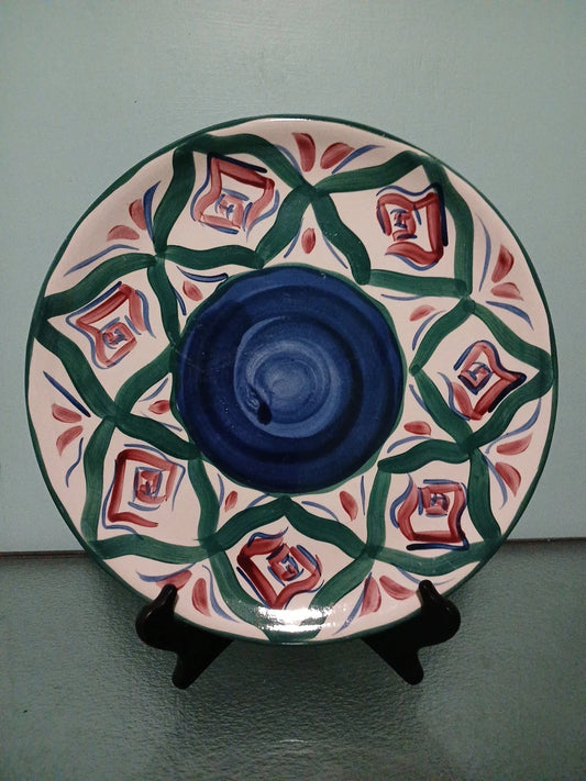 Decorative ceramic plate with geometric pattern on a stand against a plain background