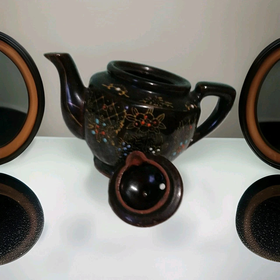 Black ceramic teapot with decorative patterns on a white surface