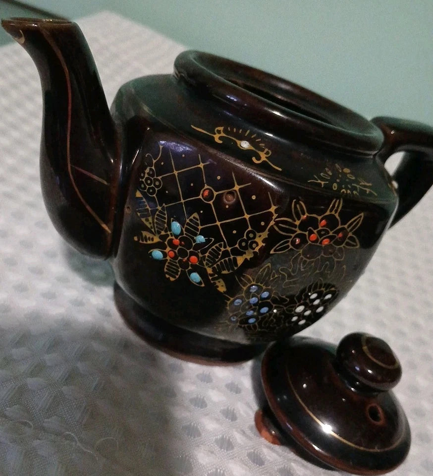 Decorative teapot with floral patterns on a textured surface